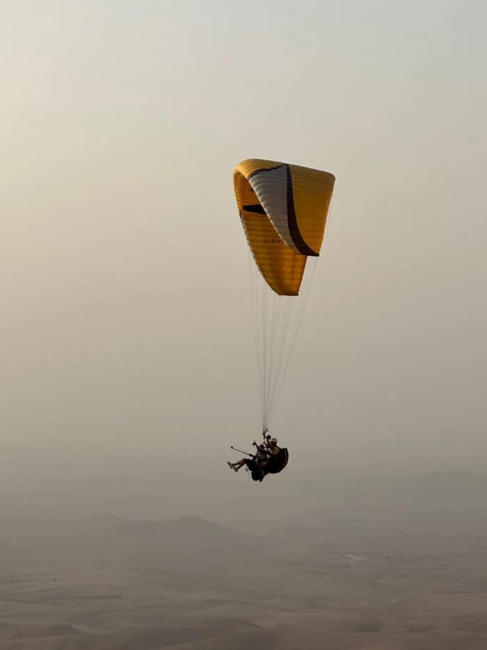 Panoramic view of paragliders soaring over Marrakech landscape at sunset